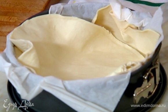 Разъемную форму выстелить бумагой для выпечки, выложить пласт теста так, чтобы получились высокие бортики.