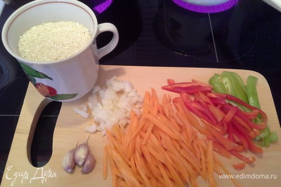 Подготавливаем овощи: моем, чистим. Режем соломкой морковь, перец. Лук режем мелким кубиком. Чеснок не очищаем, но хорошо промываем. Рис промываем водой.