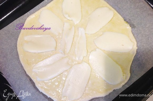 Нарежьте моцареллу тоненькими ломтиками и выложите на тесто.