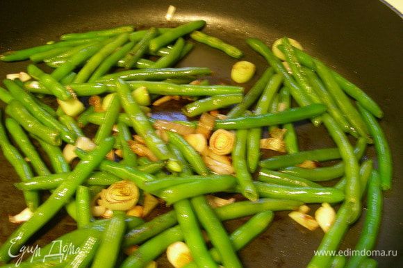 Лук обжариваем несколько минут на оливковом масле до мягкости. Добавляем фасоль и готовим еще минуту.