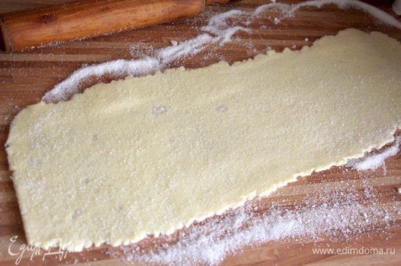Делим тесто на 2 части. Раскатываем на присыпанной сахаром поверхности в тонкий прямоугольный пласт. Сверху также присыпаем тесто сахаром.