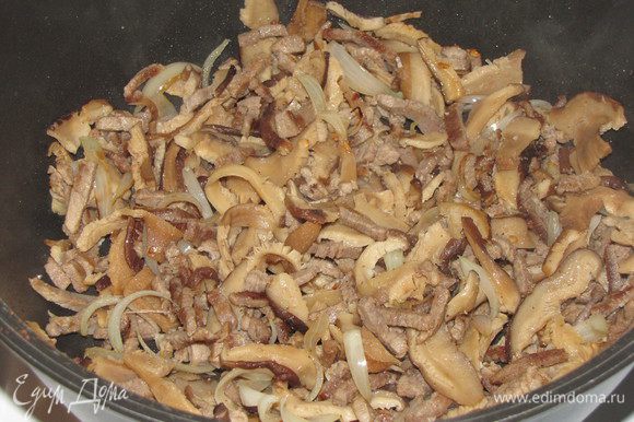 Отваренные грибы отжать и добавить к мясу. Если нужно, добавить еще кунжутное масло. Все перемешать и жарить минуты 3.