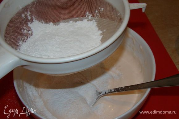 Размешивать ложкой, просеивая сахарную пудру.