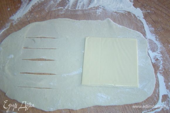 Каждый кусок теста раскатываем в тонкие прямоугольные пласты, на один край кладем сыр, а второй край надрезаем, как показано на фото.