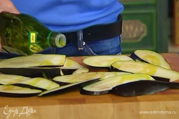 Баклажаны, удалив плодоножку, нарезать вдоль тонкими пластинами и сбрызнуть с каждой стороны оливковым маслом.