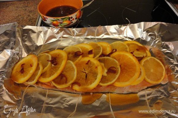 Положить первый кусок филе на фольгу. Нарезать 2-й лимон и апельсин дольками, выложить их на филе и немного полить маринадом.
