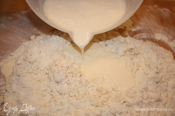 Выливаем подготовленную смесь в муку с маргарином и быстро замешиваем мягкое тесто.