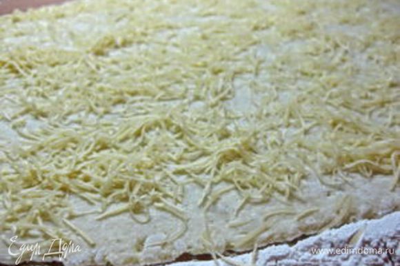 Стол посыпать мукой, выложить картофельное тесто и раскатать в большой тонкий прямоугольник. Сверху посыпать сыром.