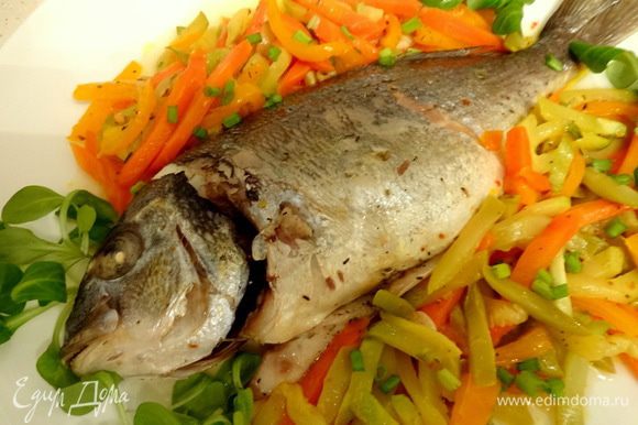 Запеченную рыбку достать из фольги, выложить вместе с овощами на тарелку. Украсить зеленью.