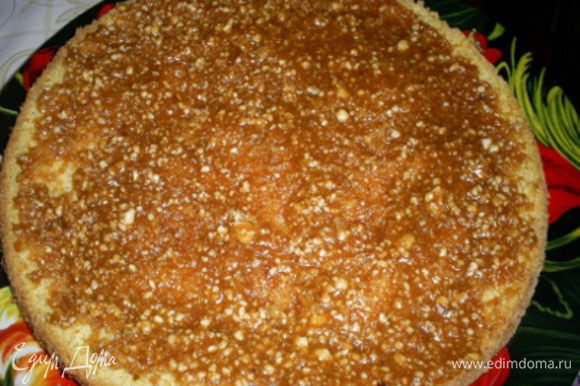 Приступаем к сборке торта. На блюдо кладем пласт бисквита срезом вверх, на него выкладываем половину карамельной прослойки, равномерно ее распределяем по поверхности.