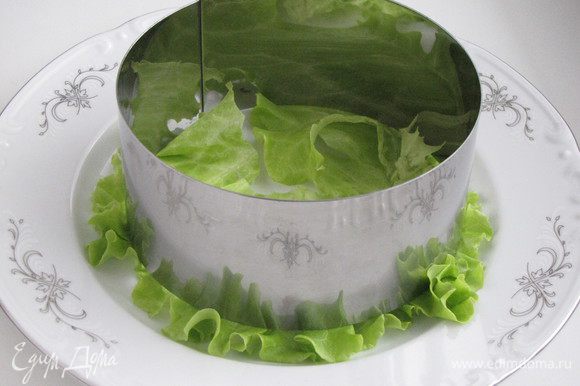 На тарелку выложить лист салата. Сверху поставить сервировочное кольцо.