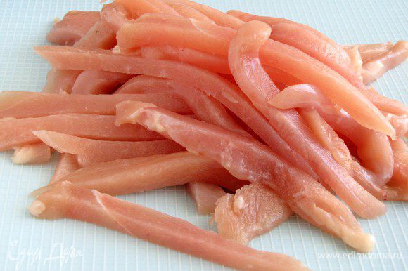 Куриное филе нарезать тонкими длинными полосками. Лучше это делать, когда мясо немного подморожено.