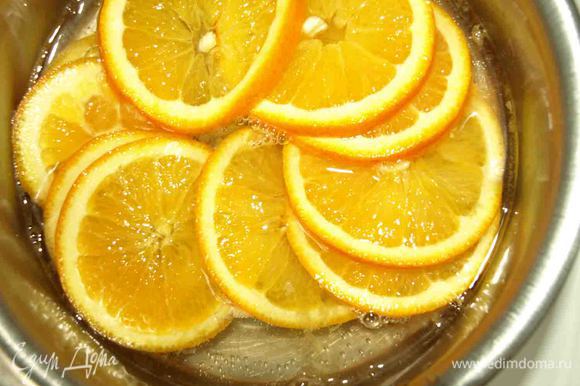 Сахар растворяем в воде, доводим до кипения. Добавляем нарезанные тонкими кружками апельсины и варим 20 минут, пока кожура не станет мягкой.