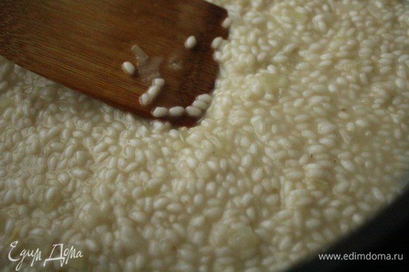 После того, как вино полностью впитается в рис, небольшими порциями влить куриный бульон. Рис нужно непрерывно перемешивать лопаткой.