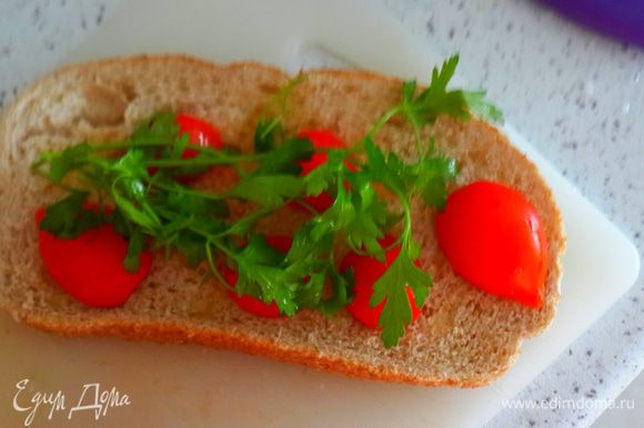 Разрезать пополам помидоры черри( но это не принципиально. Можно и другие мелкие помидорки). Положить на хлеб. Сверху петрушку.