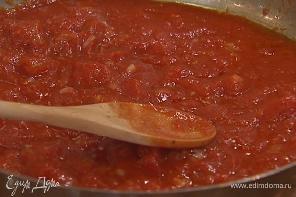 Добавить в сковороду помидоры из банки, посолить, поперчить, перемешать и потомить несколько минут на медленном огне.