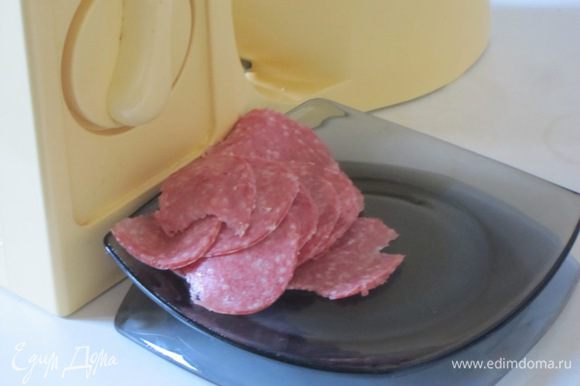 Копченую колбасу тонко нарезать электрической ломтерезкой.