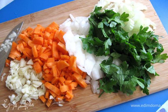 Оставшиеся лук, сельдерей и морковь мелко нарезать. Чеснок очистить, мелко порезать. К нарезанным овощам добавить листики петрушки.