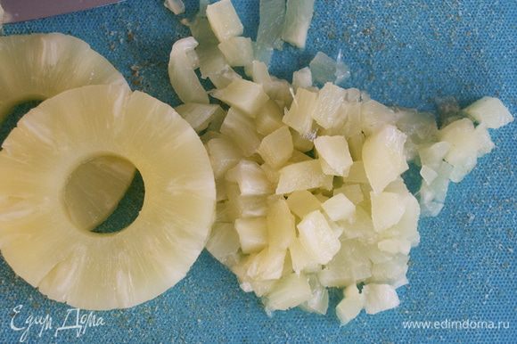 Консервированный ананас достать из банки и дать полностью стечь соку сиропу. Нарезать ананас на маленькие кубики.