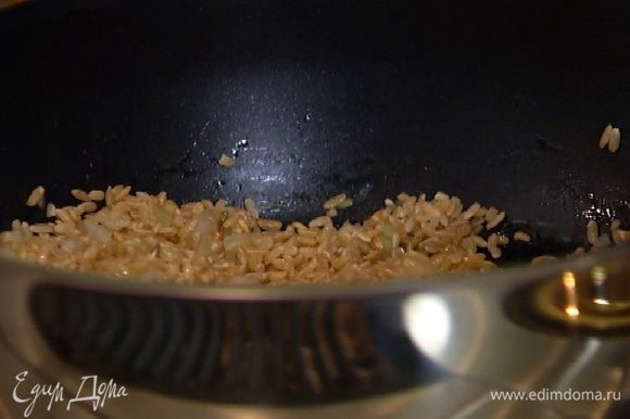 Всыпать рис и, помешивая, обжаривать около минуты, пока он не станет прозрачным.