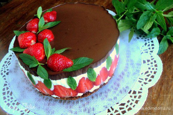 Снять с торта разъемное кольцо и бумагу для выпечки. Украсить торт клубникой и листиками свежей мяты.