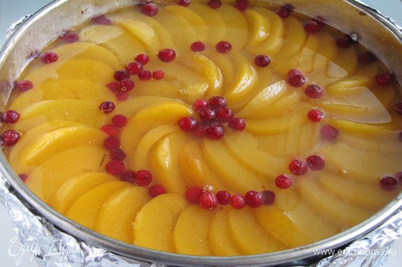 Добавить ягоды брусники по желанию. Желе развести соком от персиков и приготовить его, согласно инструкции на упаковке. Залить торт полученным желе.