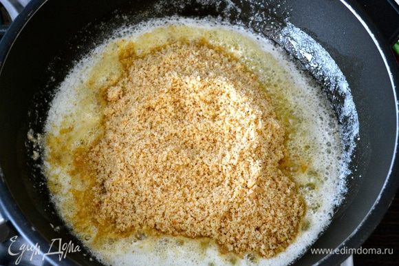 В сковороде с тяжелым дном растопить сливочное масло и добавить к нему ореховую крошку.