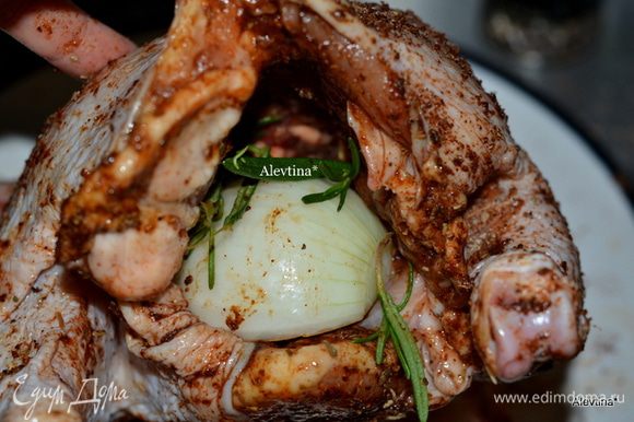 Специями смазать курицу со всех сторон и внутренность. Луковицу порезать на половинки, одну половинку положить внутрь, также веточку розмарина.