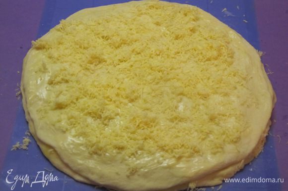 Раскатать третий кусок теста в круг, выложить на второй круг теста с сыром. Смазать растопленным сливочным маслом, посыпать тертым сыром.