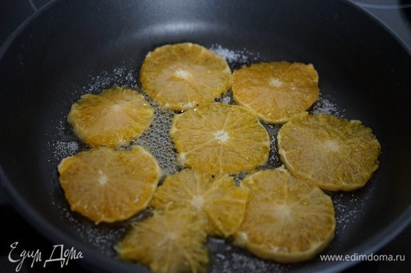 Для слоя из карамелизированных апельсинов: очистить апельсин от кожуры, лучше это сделать ножом, а не руками, срезая весь белый слой до оранжевой мякоти. Нарезать апельсин довольно тонкими кружочками, выложить их на сковороду и присыпать сахаром. Тушить в сиропе по 2-3 минуты с каждой стороны. Выложить на кекс.