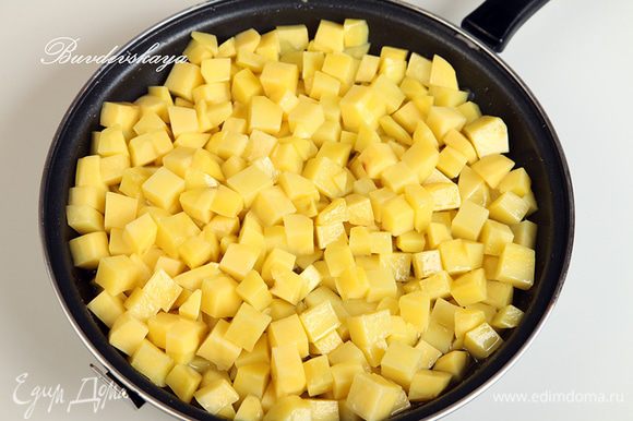 Картофель вымыть, очистить и нарезать кубиками со стороной в 1 см. В сковороде разогреть растительное масло. Не переживайте, что его слишком много: чем больше будет в сковороде масла, тем меньше его в себя впитает картофель, а излишки мы потом сольем. Выложить в сковороду картофель и уменьшить огонь до минимального. Периодически картофель необходимо помешивать лопаткой. Томить до готовности картофеля: он должен стать мягким. Внимание: нам не нужно поджарить картофель до золотистой корочки, нам нужен именно томленный картофель. Это занимает довольно много времени.