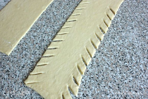 С краёв к центру под углом нарезать тесто полосками в 2 см шириной и 4 см длиной.