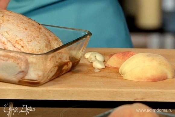 Нафаршировать курицу чесноком и персиками, уложить в смазанную маслом форму и запекать при температуре 180С около часа - до образования румяной корочки.