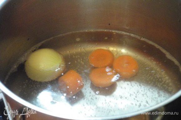 В широкую кастрюлю поместить луковицу и нарезанную крупными кусочками морковь и залить литром холодной воды. Варить 10-15 минут.