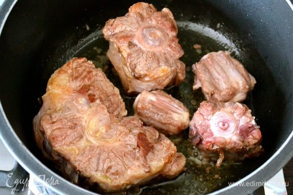 В кастрюле с толстым дном нагреть масло и обжарить куски мяса со всех сторон на сильном огне до лёгкой корочки. Достать и выложить мясо в глубокое блюдо, поддерживать в теплом состоянии.