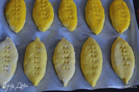 Через 15 минут смешать желток со сливками. По поверхности пирожков сделать ножницами косые надрезы (по желанию!) И смазать поверхность молочно-яичной смесью.