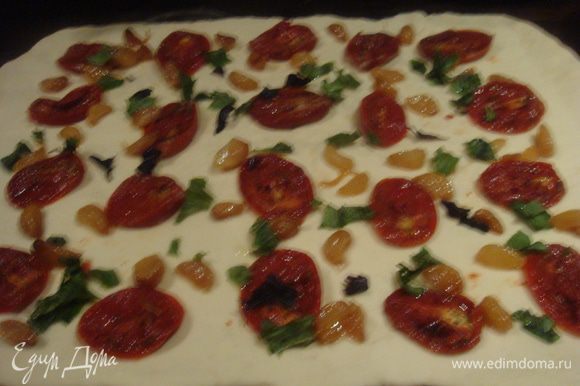 Выложить тесто на посыпанную мукой рабочую поверхность. Раскатать в прямоугольник. На тесто выложить помидоры, печеный чеснок и базилик.