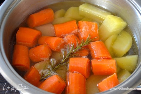 Очистить морковь и картофель. Одну морковку отложить в сторону. Остальные овощи нарезать кусочками, выложить в кастрюлю и залить холодной водой. Поставить на огонь, довести до кипения и варить 30 минут (я добавила веточку розмарина).