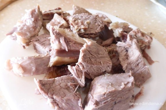 Готовое мясо извлечь из кастрюли, порезать на порционные кусочки и положить снова в бульон.