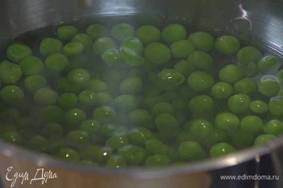 Размороженный зеленый горошек опустить на две минуты в кипящую воду, затем откинуть на дуршлаг.