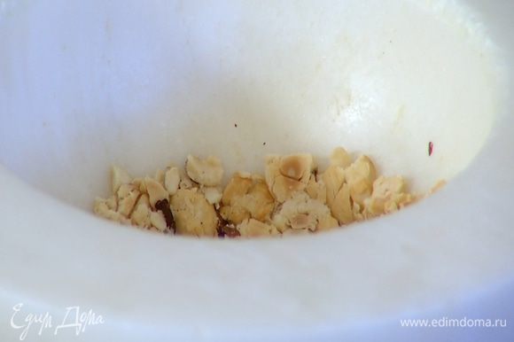 Половину орехов измельчить в ступке в крупную крошку, добавить во взбитые сливки и перемешать.