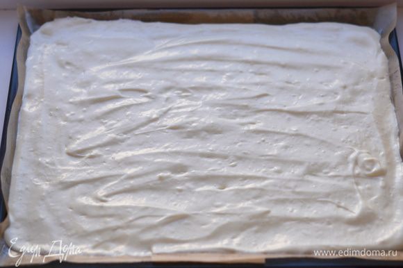 Противень застелить пекарской бумагой, смазать сливочным маслом. Выложить бисквитное тесто, разровнять спатулой.