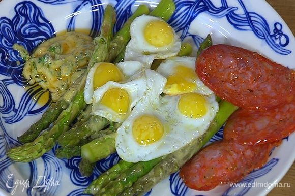Выложить спаржу вместе с соусом на тарелку, сверху поместить перепелиные яйца и кусочки колбасы.