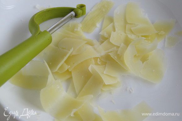 Нарезать сыр тонкой стружкой при помощи ножа для чистки овощей.