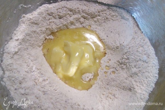 Сделайте в смеси лунку и влейте размягченное масло, замесите руками тесто.
