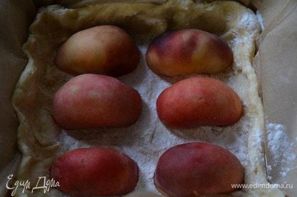 Форму с тестом достать из холодильника, присыпать крахмалом и уложить половинки персиков срезом вниз.