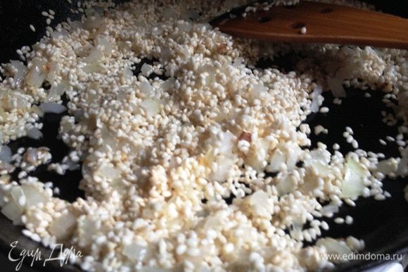 Добавить в сотейник рис. Продолжать жарить помешивая, пока рис не станет прозрачным. Добавить очищенный и измельчённый чеснок, оба вида паприки, перемешать.