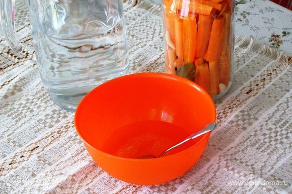 Когда морковка в банке уложена до верха, подготовим маринад. Для этого растворим в мисочке соль, сахар в небольшом количестве воды и добавим уксус.