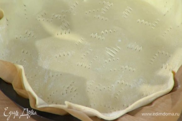 Форму выстелить бумагой для выпечки, выложить тесто, сформировав бортики, и часто наколоть его вилкой.