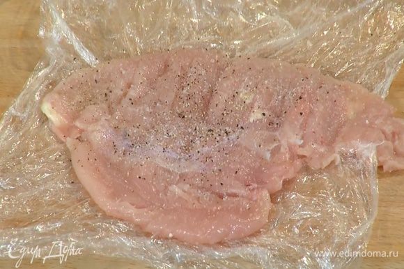 Куриное мясо поместить между двумя слоями пищевой пленки, отбить скалкой, затем посолить и поперчить с обеих сторон.